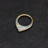 Anillo de septum dorado con ópalo sintético brillante sobre fondo oscuro