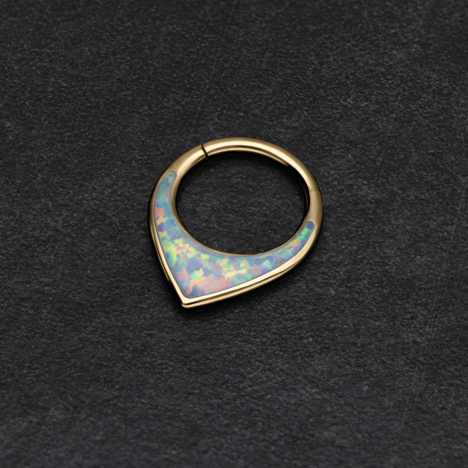Anillo de septum dorado con ópalo sintético brillante sobre fondo oscuro