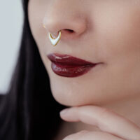 Mujer con clicker de septum dorado de titanio y ópalo blanco sobre fondo neutro