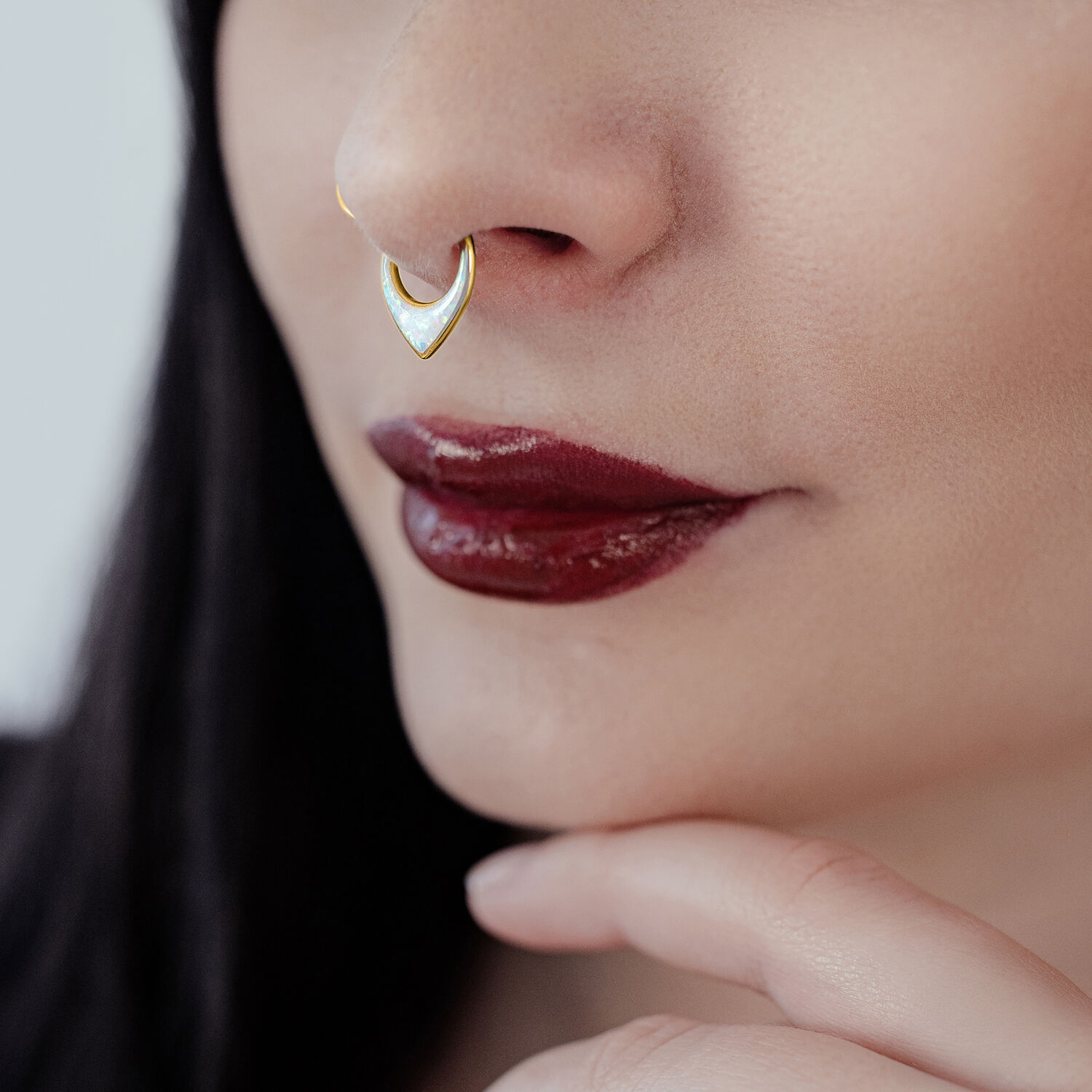 Mujer con clicker de septum dorado de titanio y ópalo blanco sobre fondo neutro