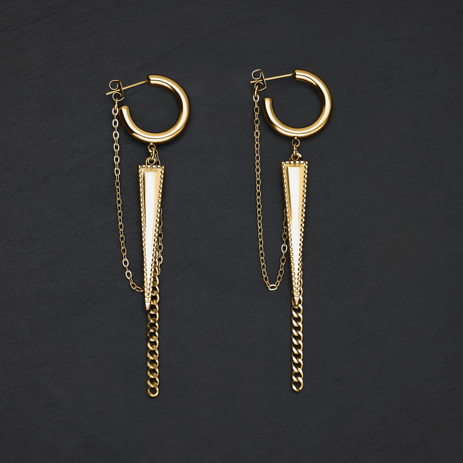 Pendientes dorados en forma de triángulo con colgante de cadena sobre fondo oscuro