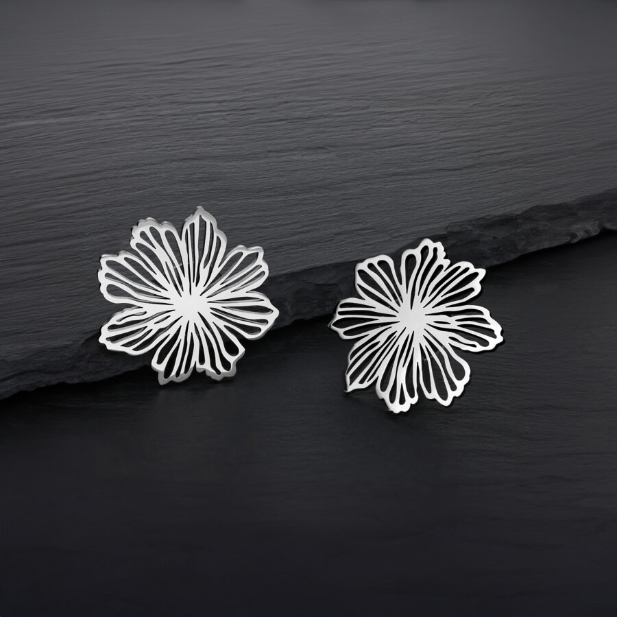 Dos pendientes de flores plateadas de acero inoxidable sobre fondo oscuro