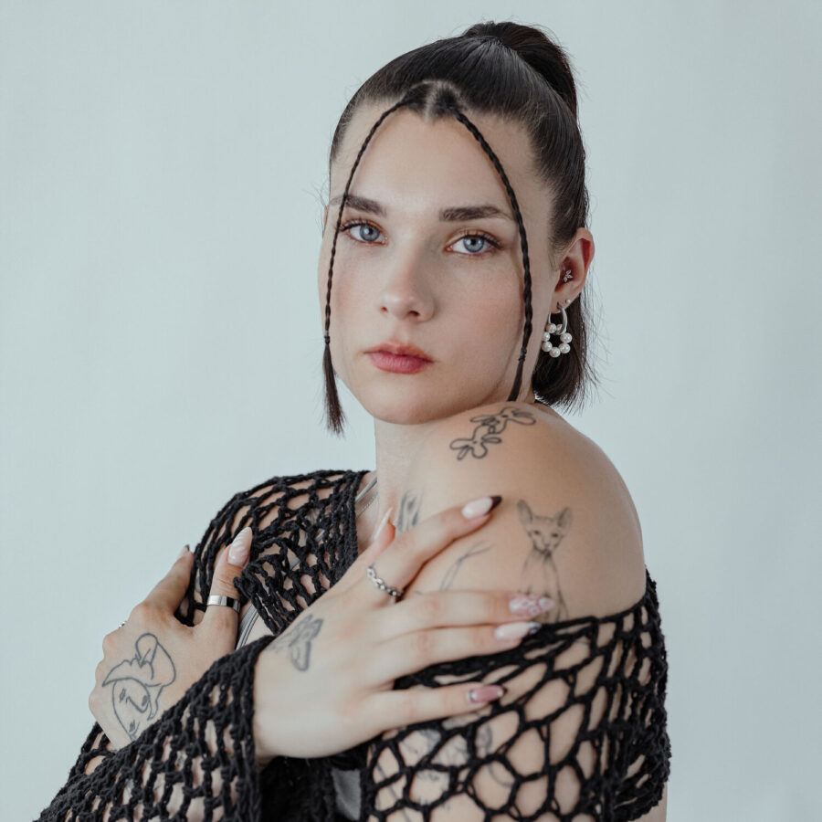 Mujer con pendientes Little Pearl Circle Hoops y top negro frente a un fondo neutro
