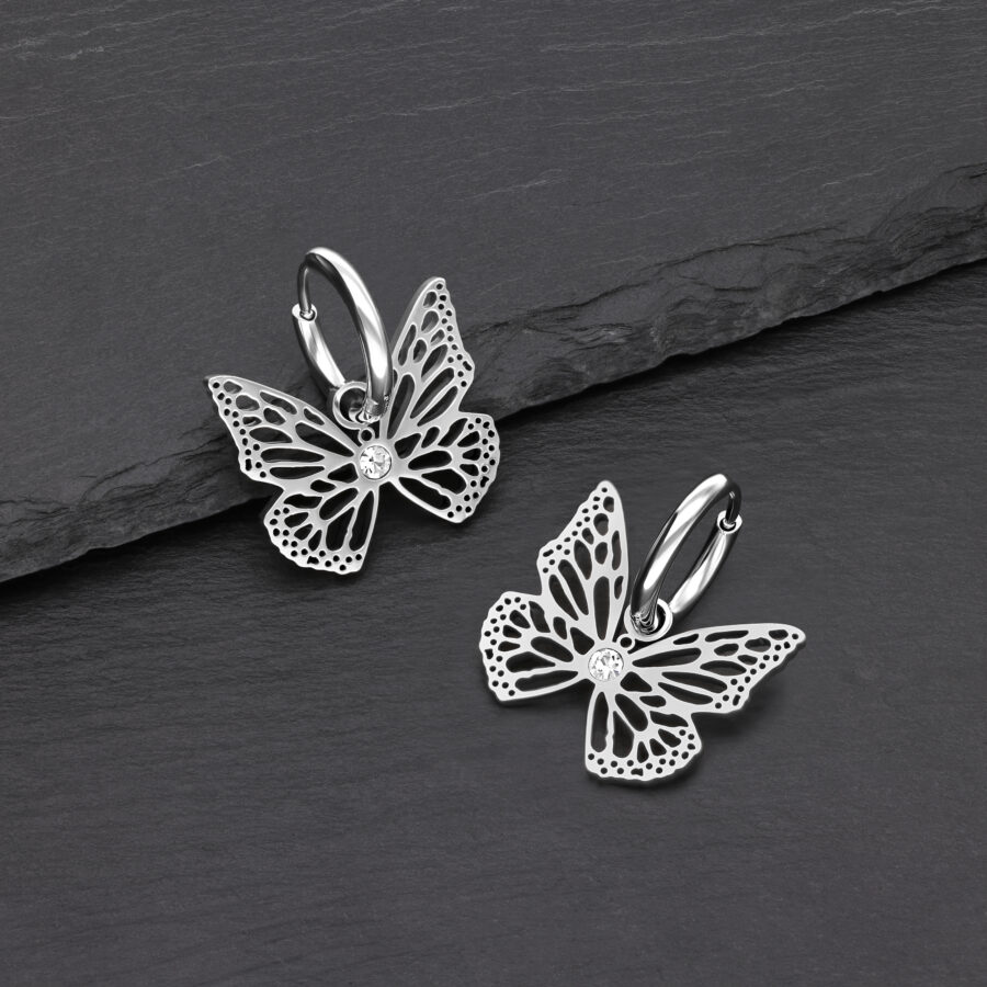 Dos pendientes de mariposa plateados de acero inoxidable sobre fondo negro