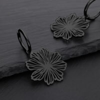 Pendientes de flores negras de acero quirúrgico sobre fondo gris