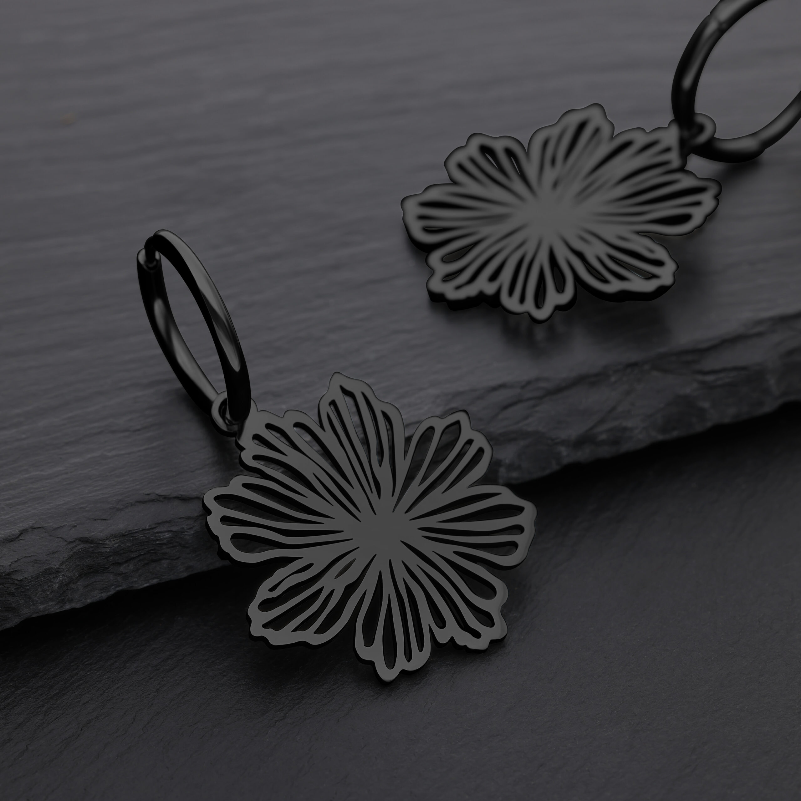 Pendientes de flores negras de acero quirúrgico sobre fondo gris