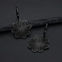 Pendientes negros en forma de flor de acero quirúrgico sobre fondo gris