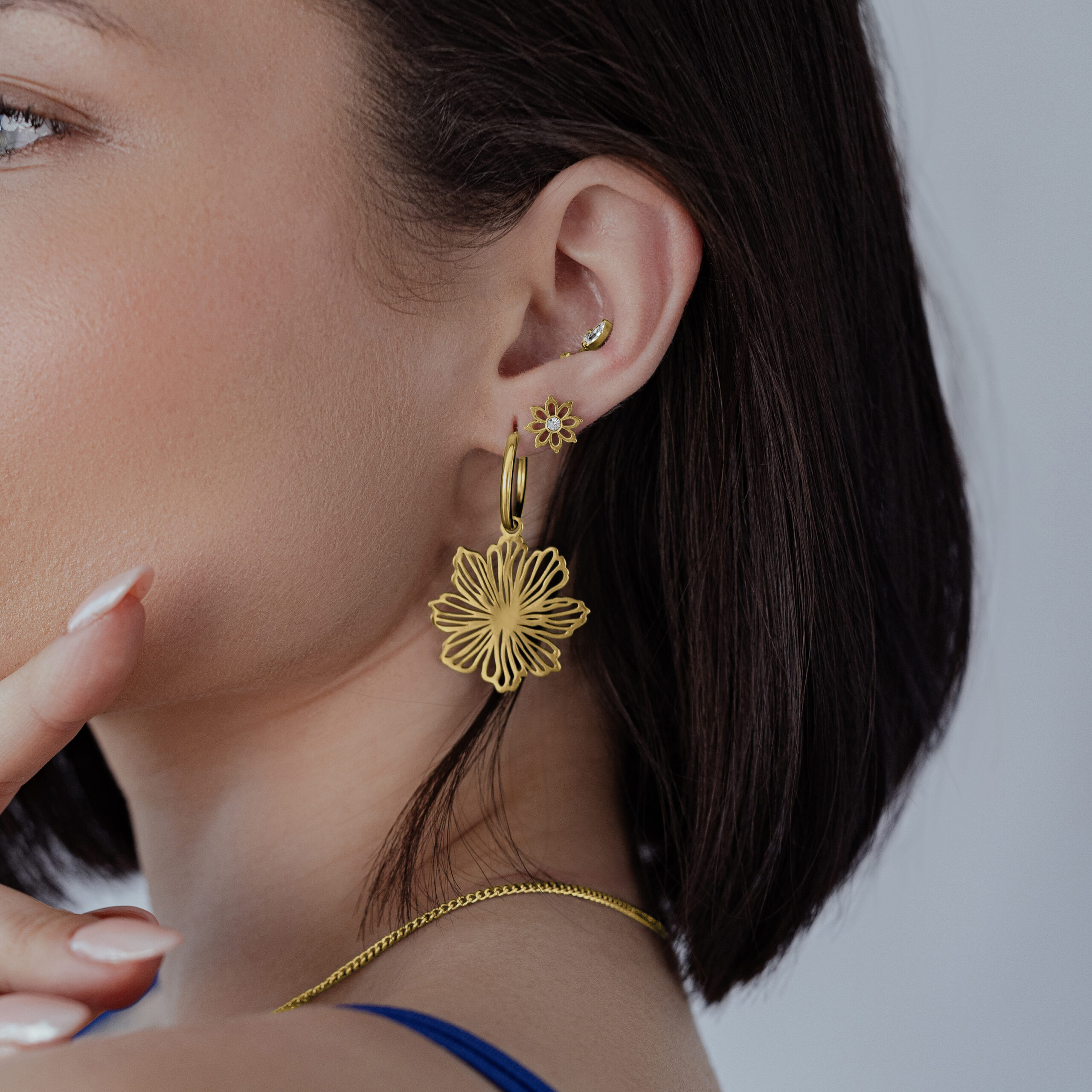 Aros Dorados Fine Flower Hoops Mujer lleva aros dorados Fine Flower Hoops frente a un fondo neutro