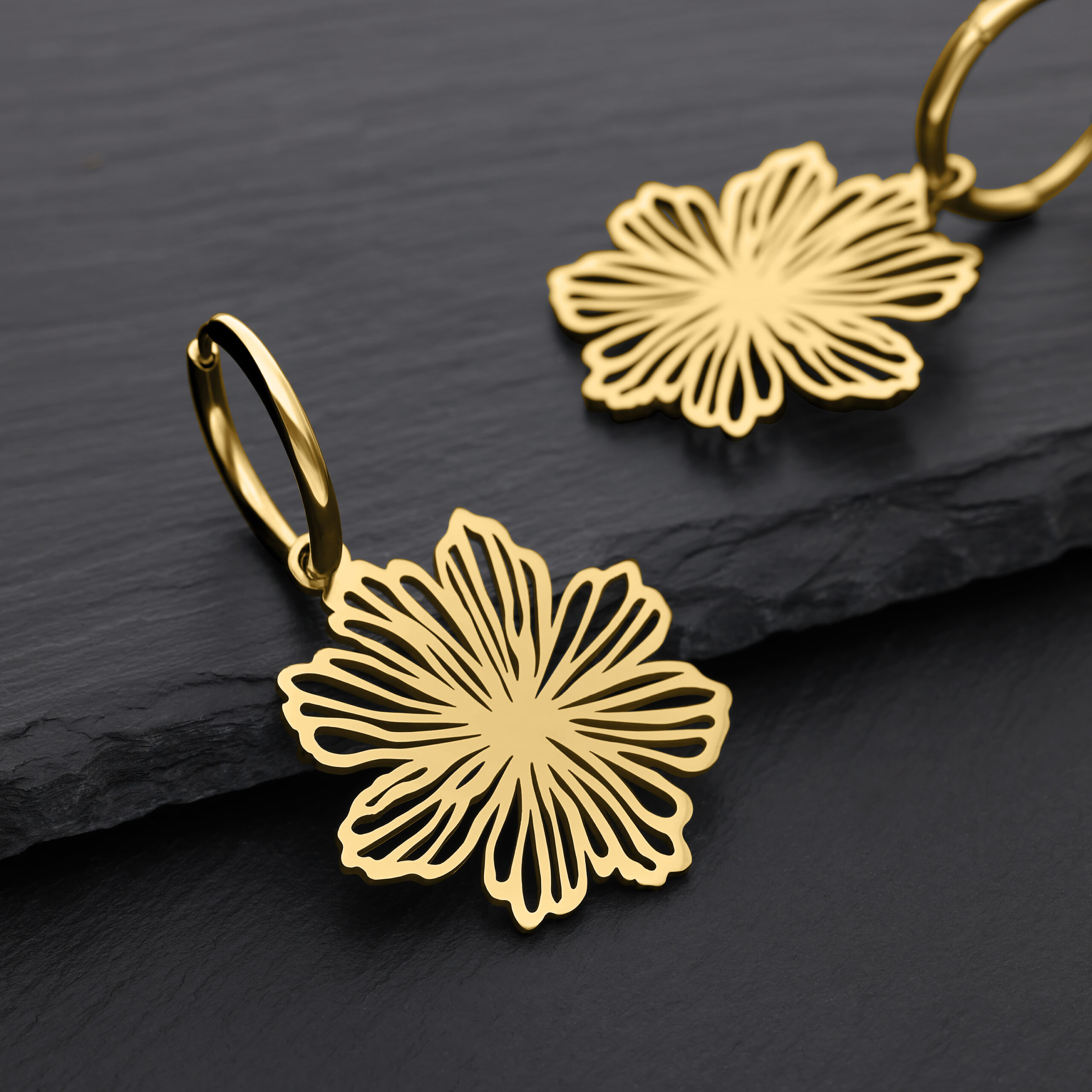 Aros Fine Flower dorados de acero quirúrgico Dos pendientes dorados en forma de flor sobre fondo negro