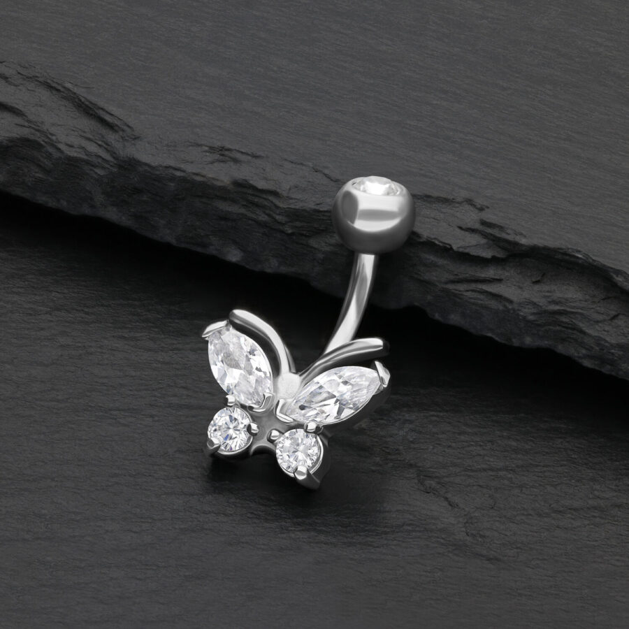 Piercing de ombligo plateado con mariposa y cristales claros sobre fondo negro