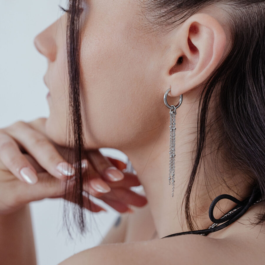 Pendientes de acero inoxidable plateados con cadenas en la oreja de un modelo