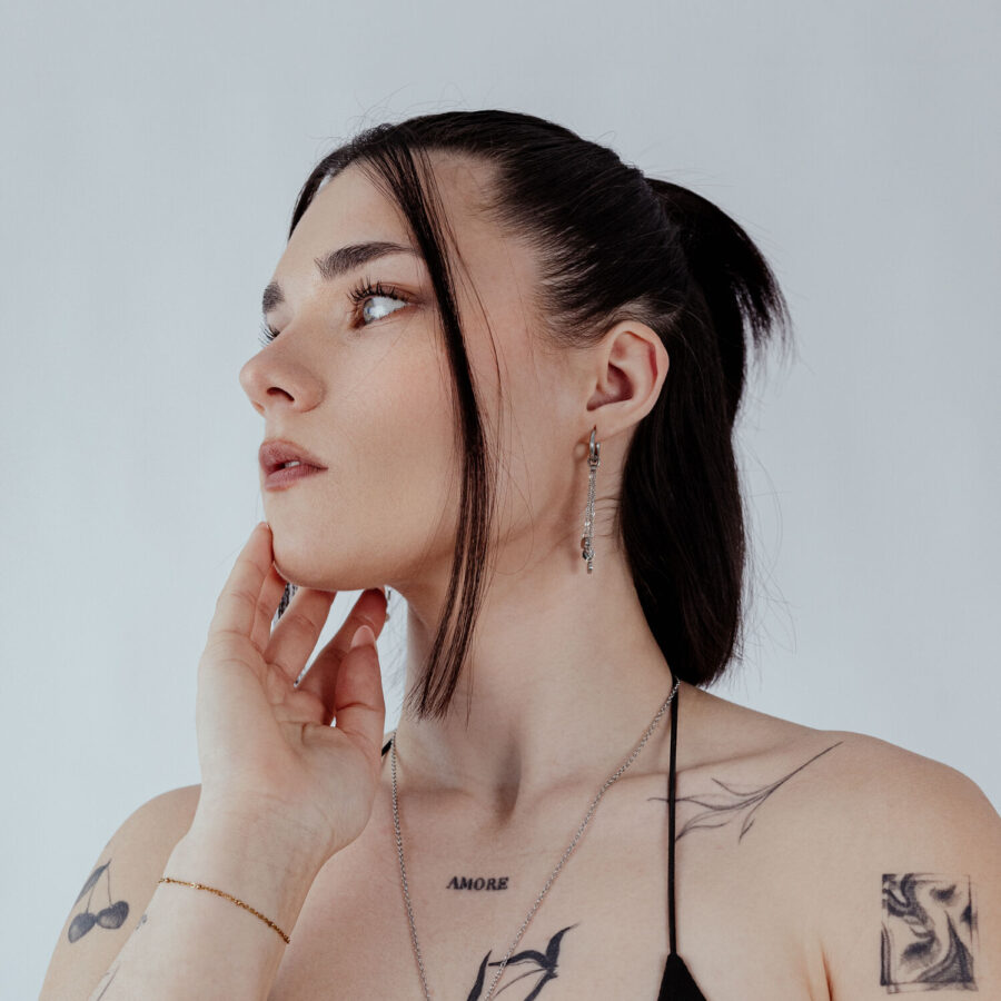 Mujer con aros negros y plateados, fotografiada de lado