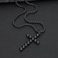 Schwarze Halskette mit Kreuzanhänger aus Kugeln auf dunklem Hintergrund