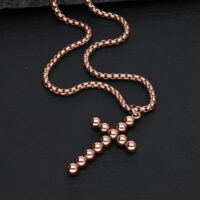 Roségoldene Halskette mit Kreuzanhänger aus Kugeln auf schwarzem Hintergrund