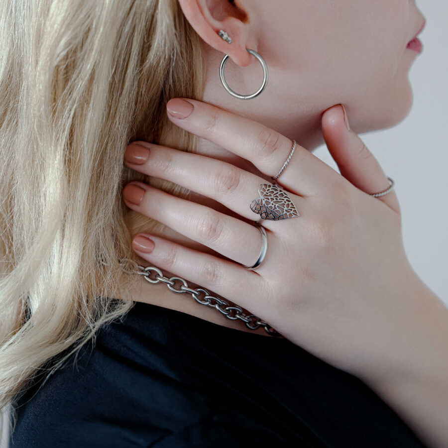 Anillo Lovely Leaf Plateado en la mano de una mujer que sostiene una cadena