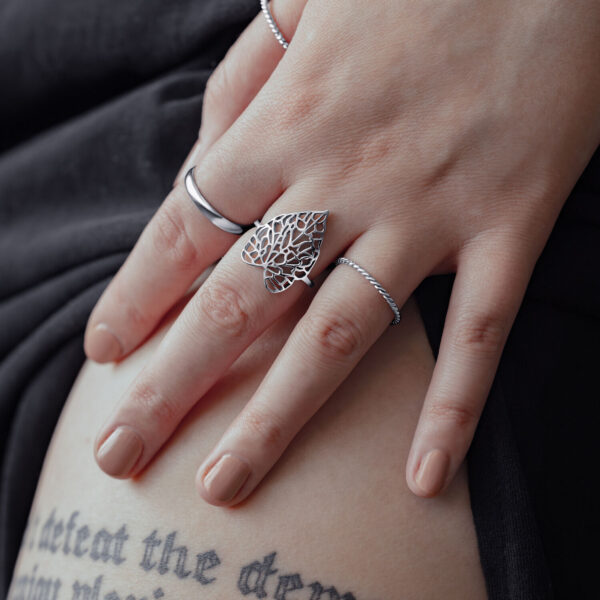 Anillo de plata con diseño de hoja en mano femenina sobre fondo negro