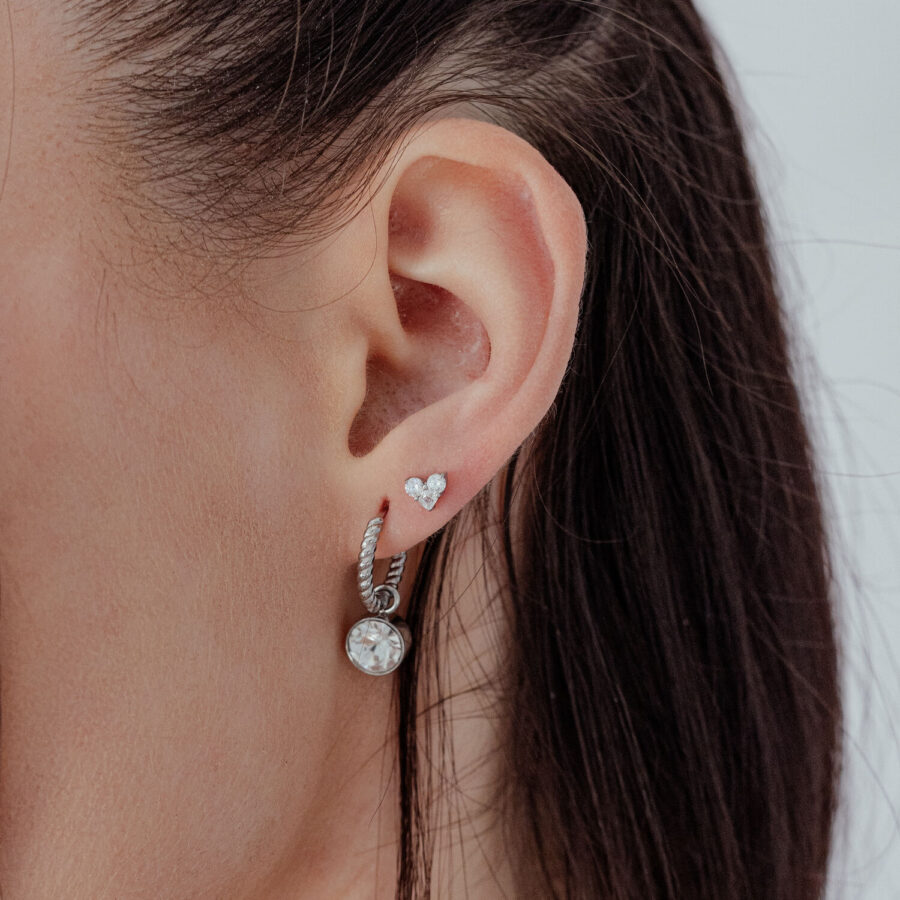 Aro de corazón plateado con piedra cristalina en la oreja, vista lateral