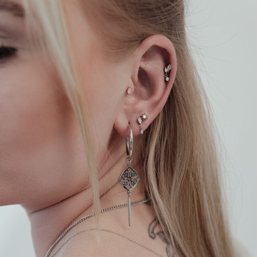 Primer plano de una oreja con varios piercings, incluyendo un gran Push Fit Cristal Estrella plateado.
