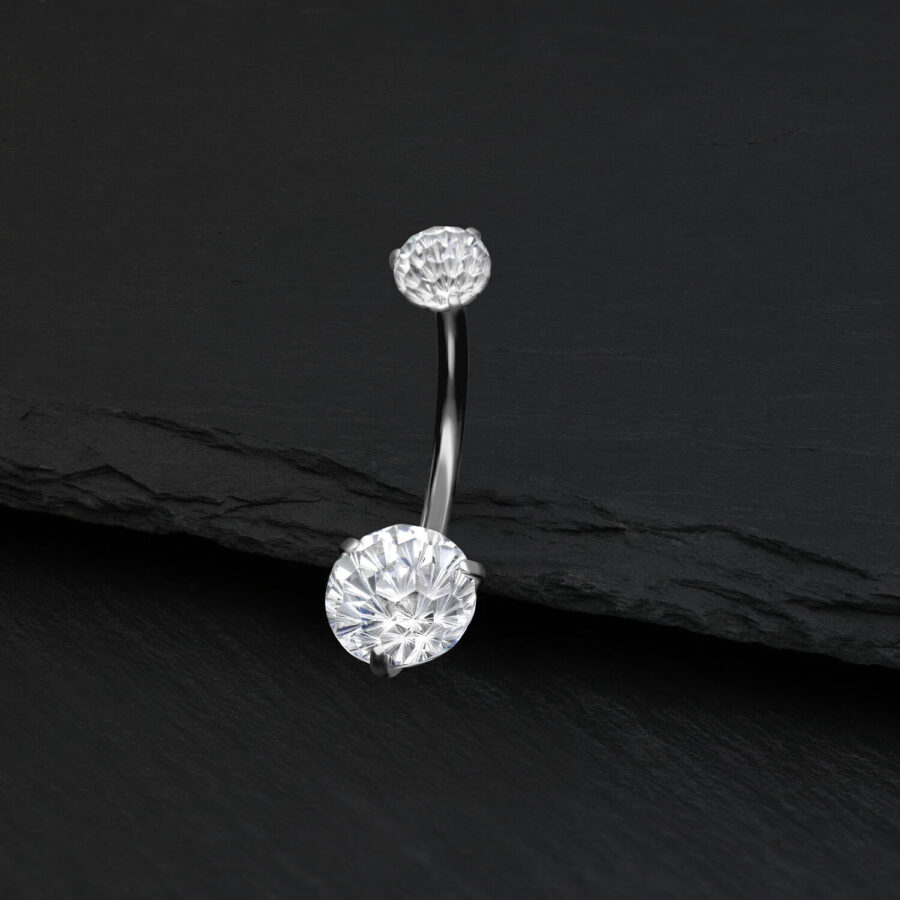 Piercing de ombligo plateado con cristal claro sobre fondo negro
