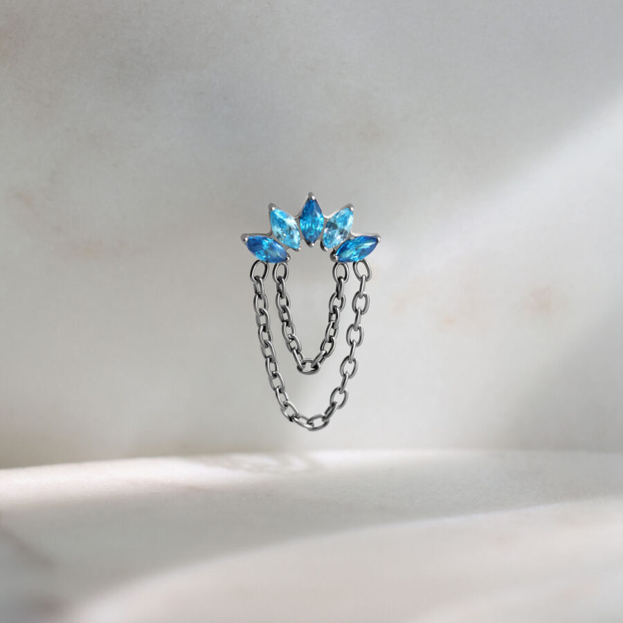 Adorno de piercing Push Fit plateado con tres cristales turquesa sobre fondo claro
