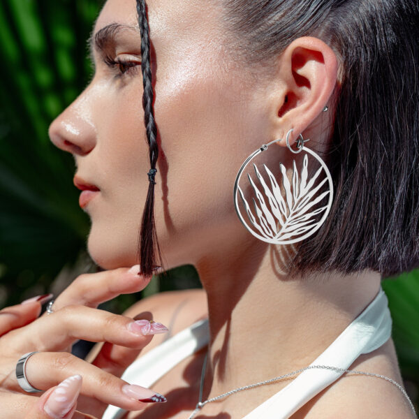Pendientes Noble Leaf Hoops plateados en mujer con cabello trenzado y fondo tropical