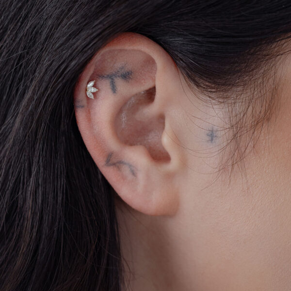 Accesorio Flor de Lotus de 14K Gold en la oreja de una persona con cabello oscuro