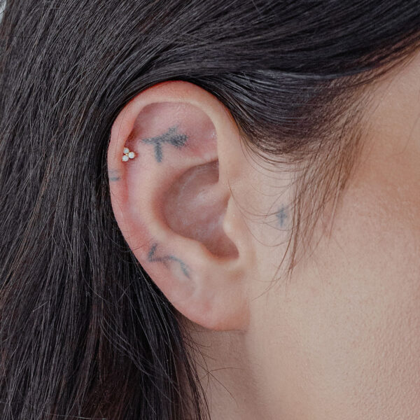Accesorio de oro con ópalo sintético en un piercing de oreja