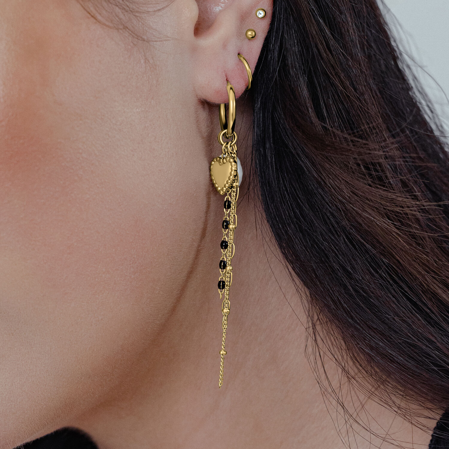 Goldene Ohrringe in Herzform an einem Ohr, detailreiches Design