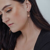 Frau mit Bubble Heart Hoops in Roségold, langes Design, an Ohr getragen