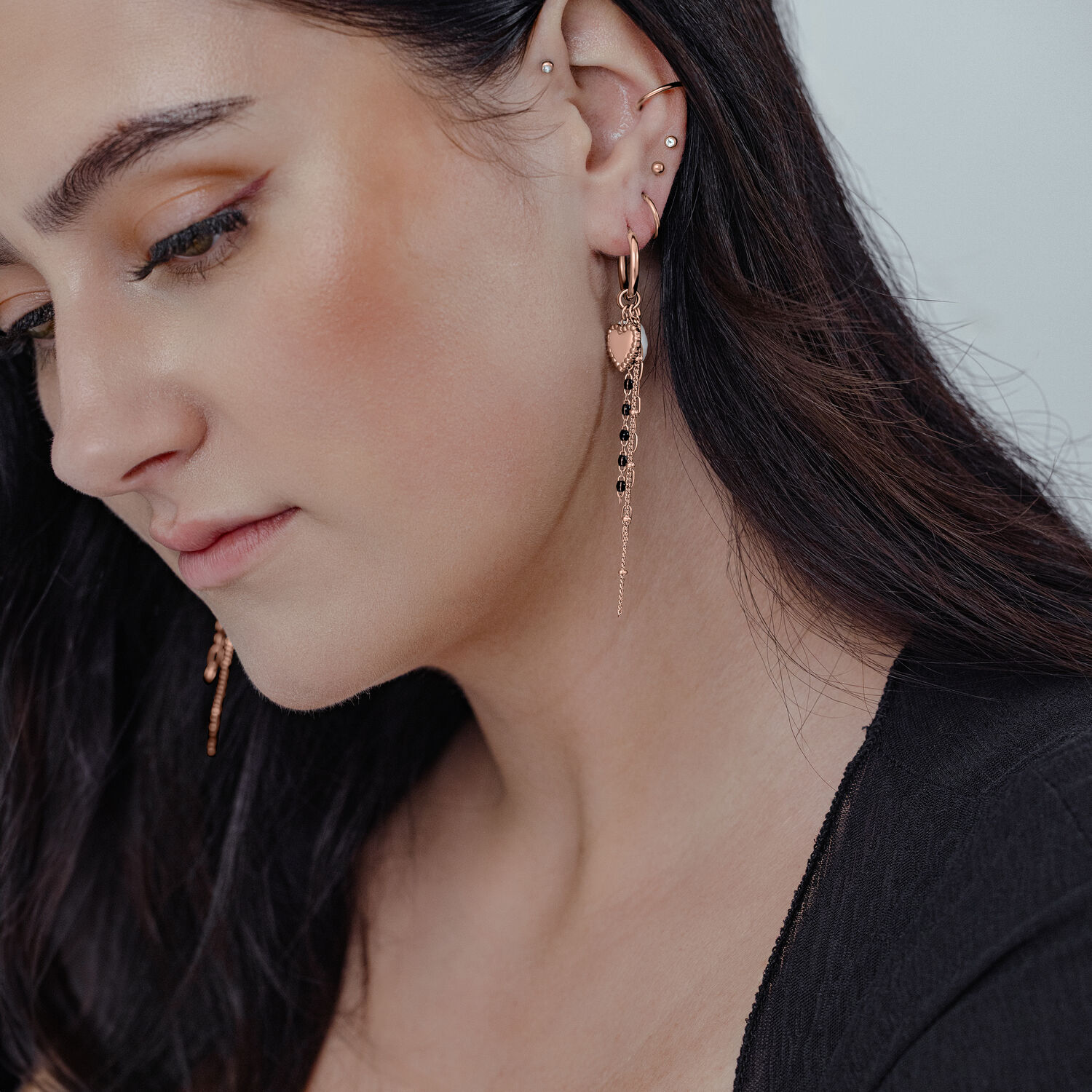 Frau mit Bubble Heart Hoops in Roségold, langes Design, an Ohr getragen