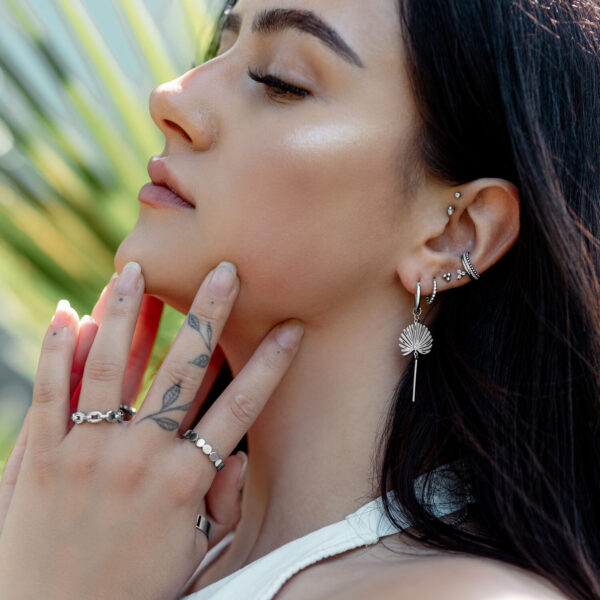 Mujer con varios pendientes, incluyendo Little Petticoat Hoops, en la oreja, al aire libre