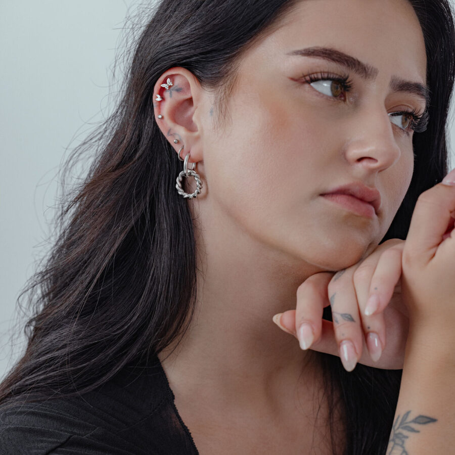 Mujer con cabello largo lleva Twisted Circle Hoops plateados, perfil lateral