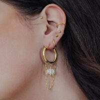 Goldene Edgy Stone Hoops mit Kettenanhänger am Ohr einer Person