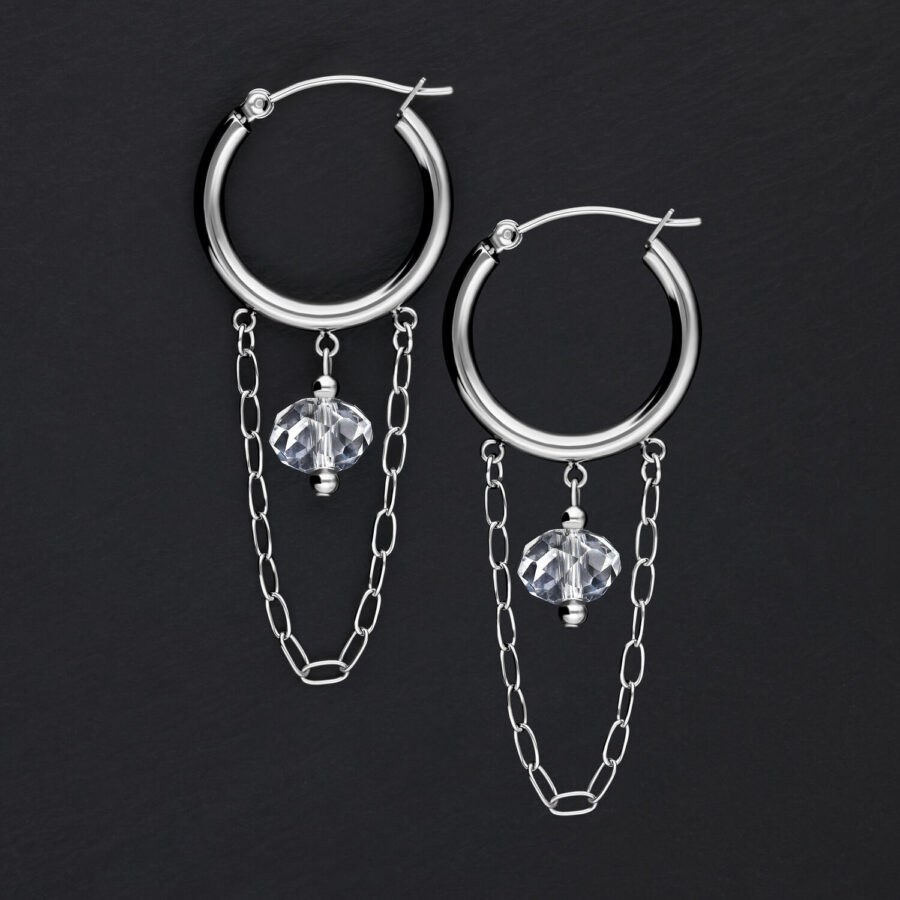 Aros plateados con cadenas y piedras sobre fondo negro