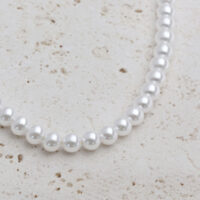Gran collar de perlas sintéticas con elementos metálicos dorados sobre fondo claro