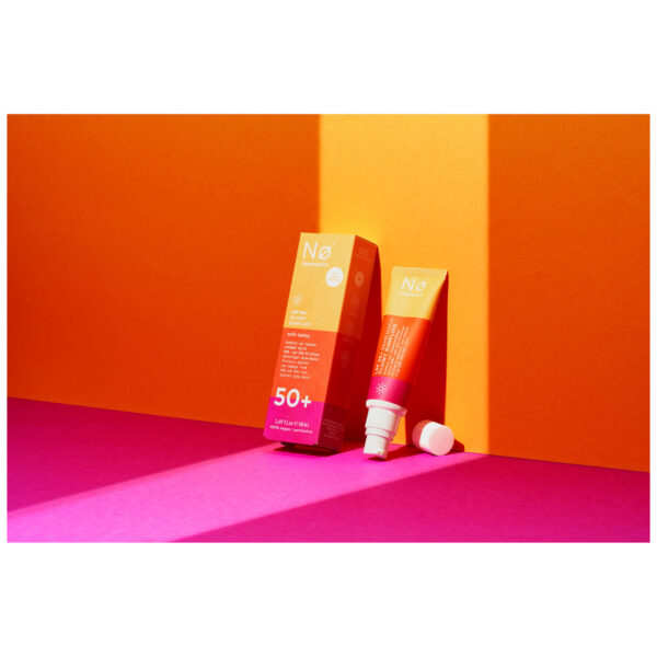 No Cosmetics Glowy Sunfluid en tubo frente a fondo naranja y rosa