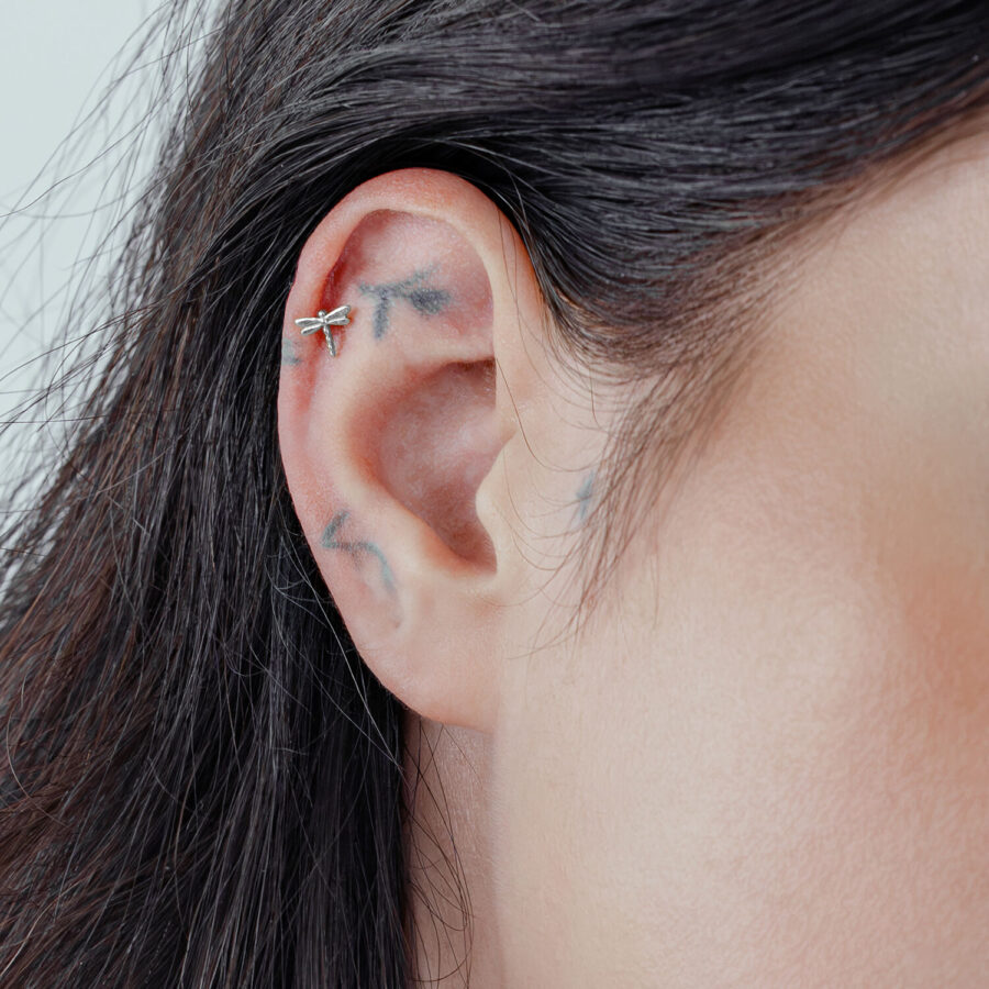 Encaje a presión de libélula plateada en piercing de oreja sobre fondo claro
