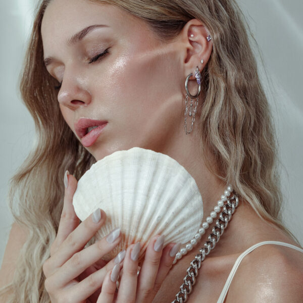 Mujer con accesorio de piercing y concha, pendientes de plata y oro