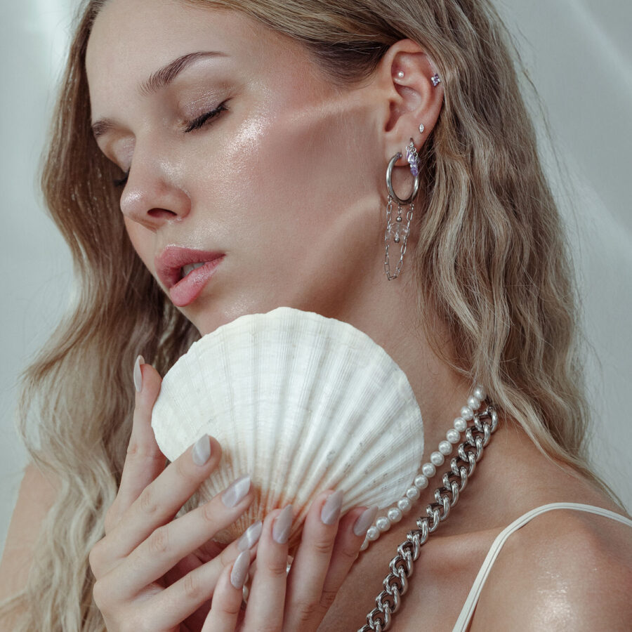 Mujer con accesorio de piercing y concha, pendientes de plata y oro
