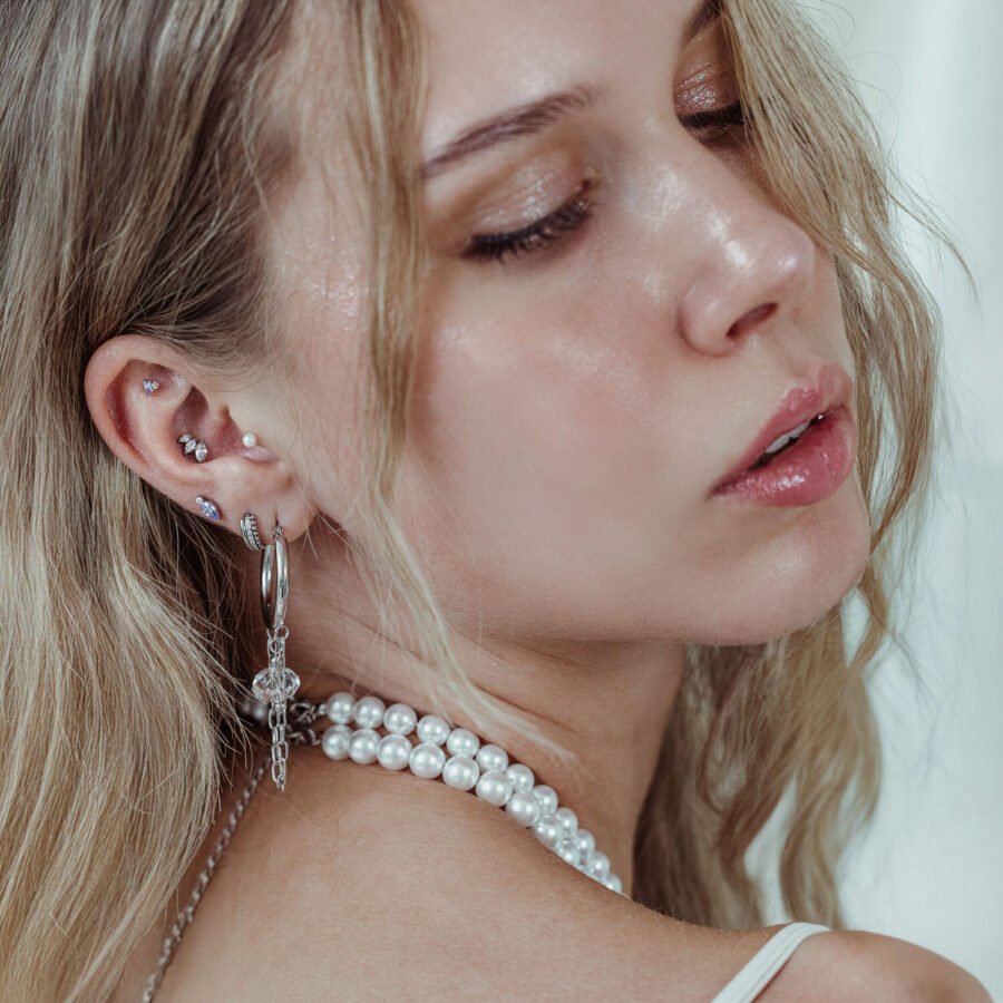 Primer plano de una oreja con accesorio Push Fit plateado y cristal lavanda, usado por una mujer rubia