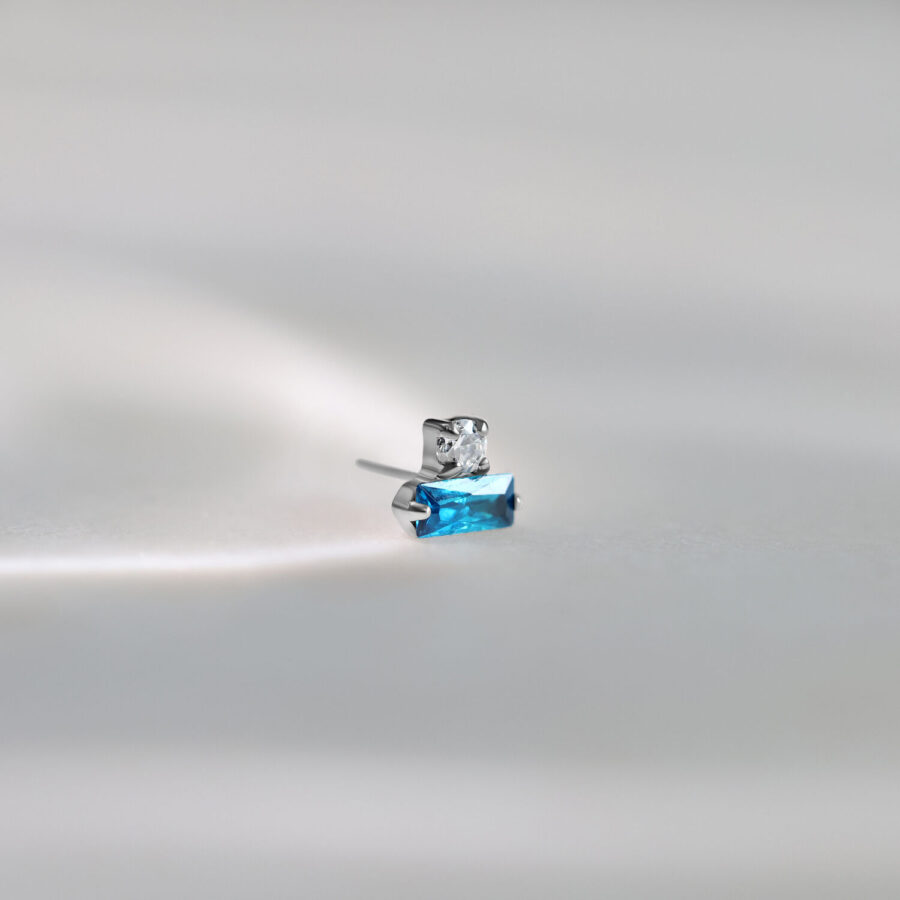 Ajuste de piercing de plata con cristal rectangular turquesa sobre fondo gris