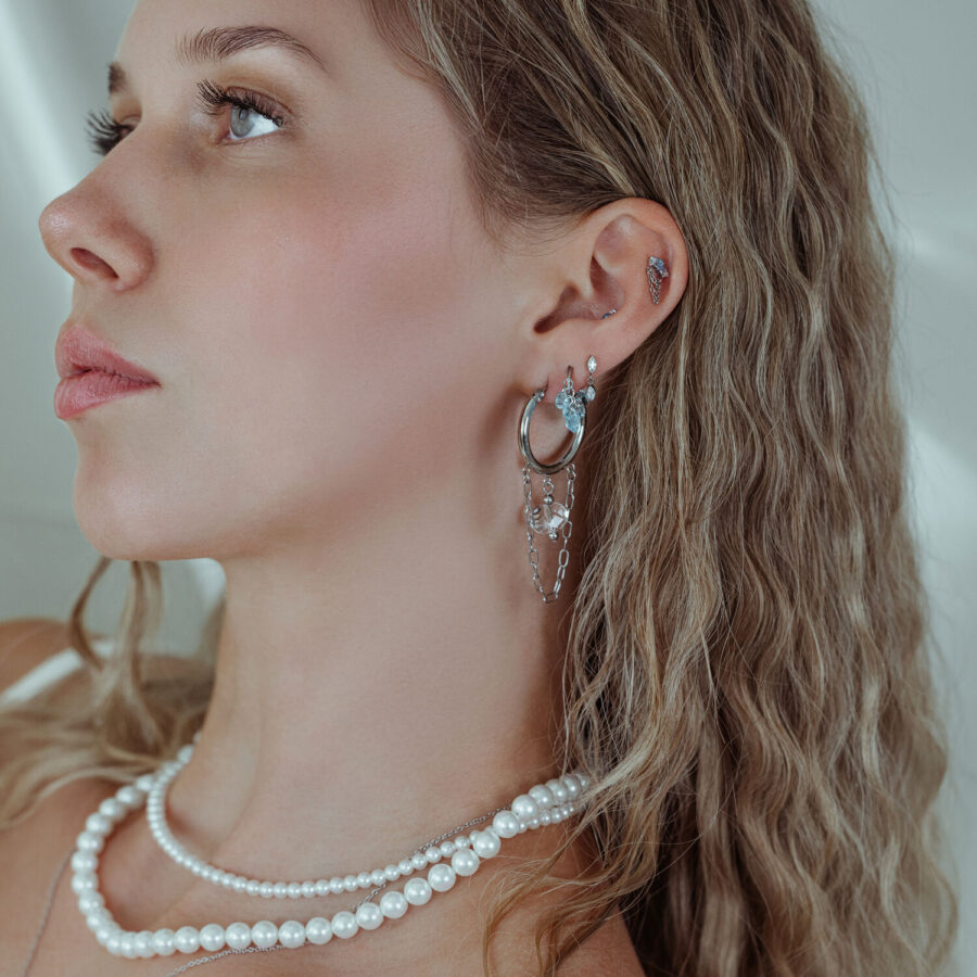 Mujer con piercings de oreja plateados y cristales, primer plano