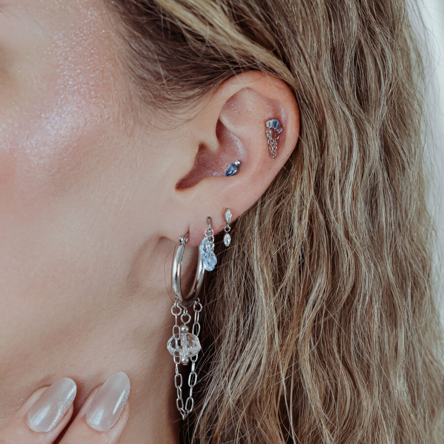 Oreja con varios piercings, incluido un accesorio Mystic Dew plateado