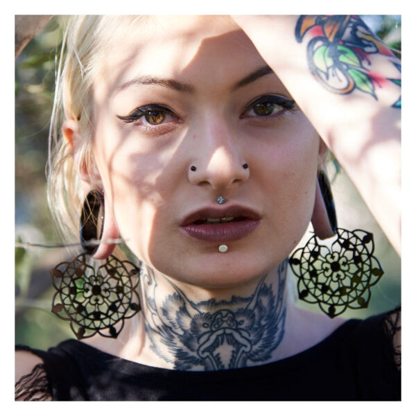 Mujer con grandes pendientes florales negros de acero quirúrgico