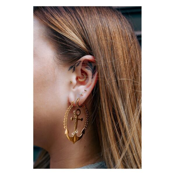 Mujer con piercings dorados en el oído, incluyendo un Little Balls Crystal Clicker