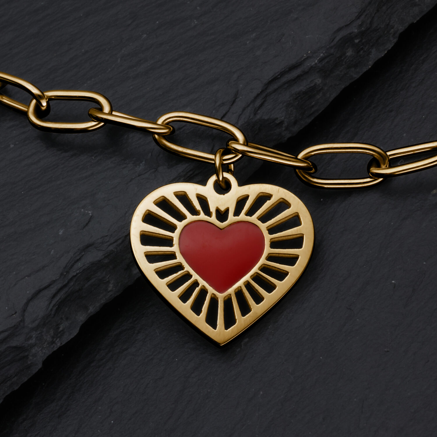 Pulsera Sacred Heart dorada con corazón rojo Pulsera de metal dorado con colgante en forma de corazón y corazón rojo sobre fondo de pizarra