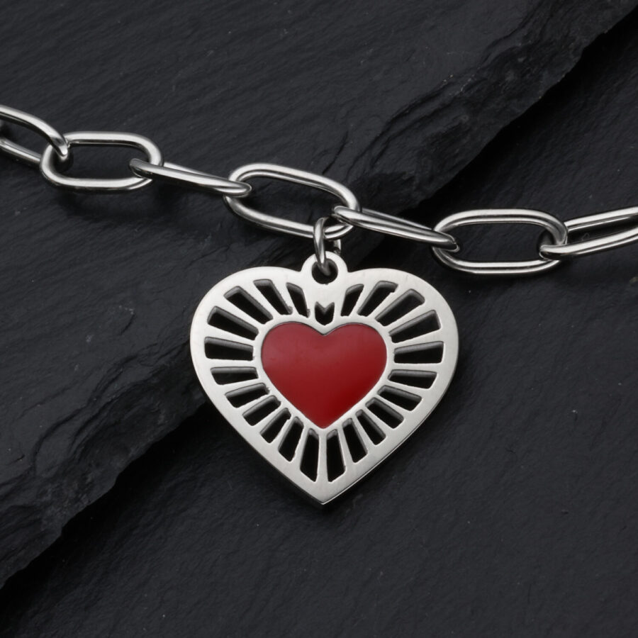 Pulsera plateada con colgante de corazón rojo sobre fondo oscuro