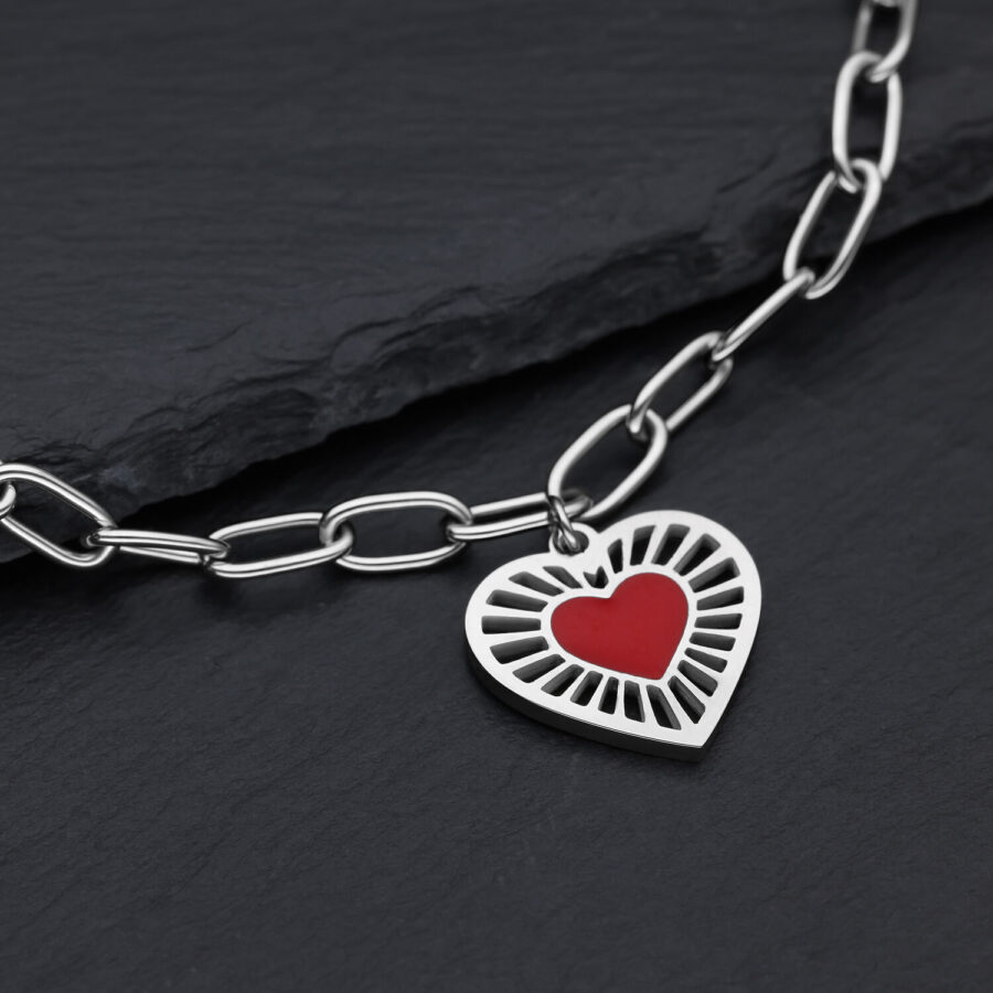 Pulsera plateada de acero quirúrgico con colgante de corazón rojo sobre fondo oscuro