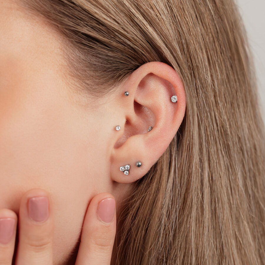 Primer plano de una oreja con varios piercings de titanio en negro y plata