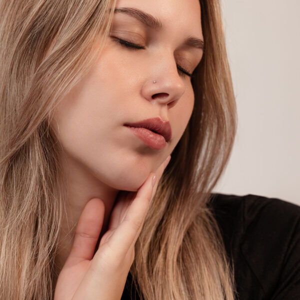 Mujer con ojo cerrado, lleva elegante perno nasal de titanio negro